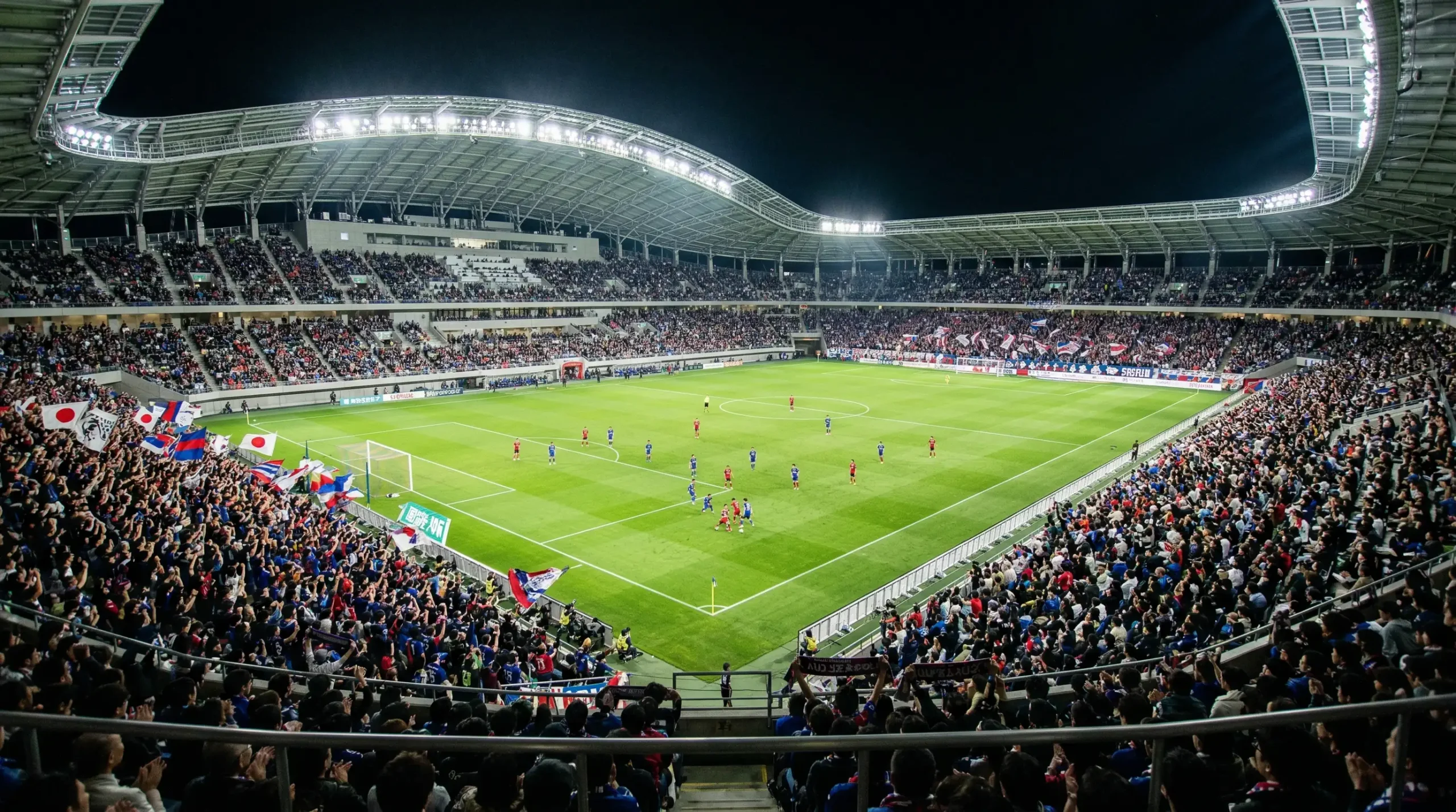 Estadio de la J League con ambiente nocturno y afición japonesa