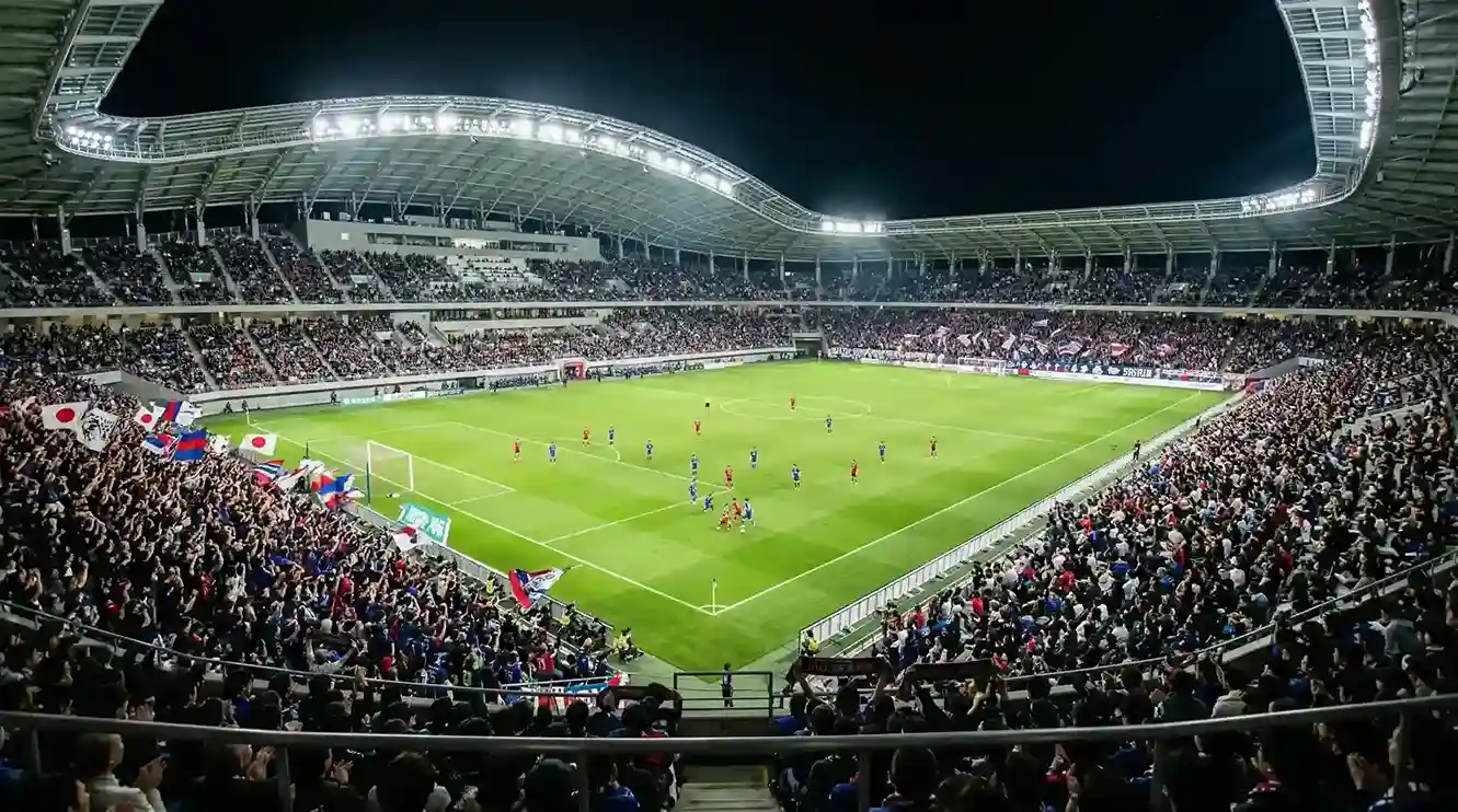 Estadio de la J League con ambiente nocturno y afición japonesa